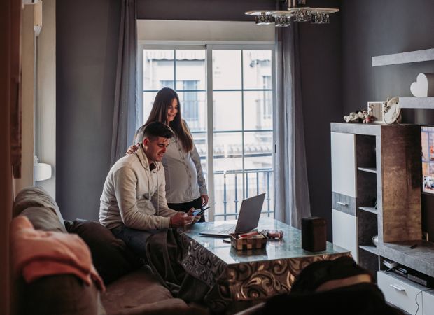 Couple expecting baby using gadgets at home