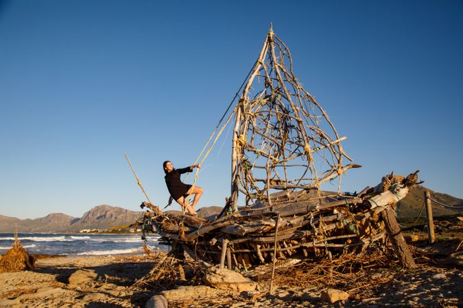 Young woman on decorative wooden ship near water on shore