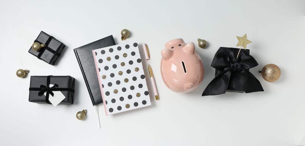 Piggy bank, gift boxes and notepads on neutral background, top view