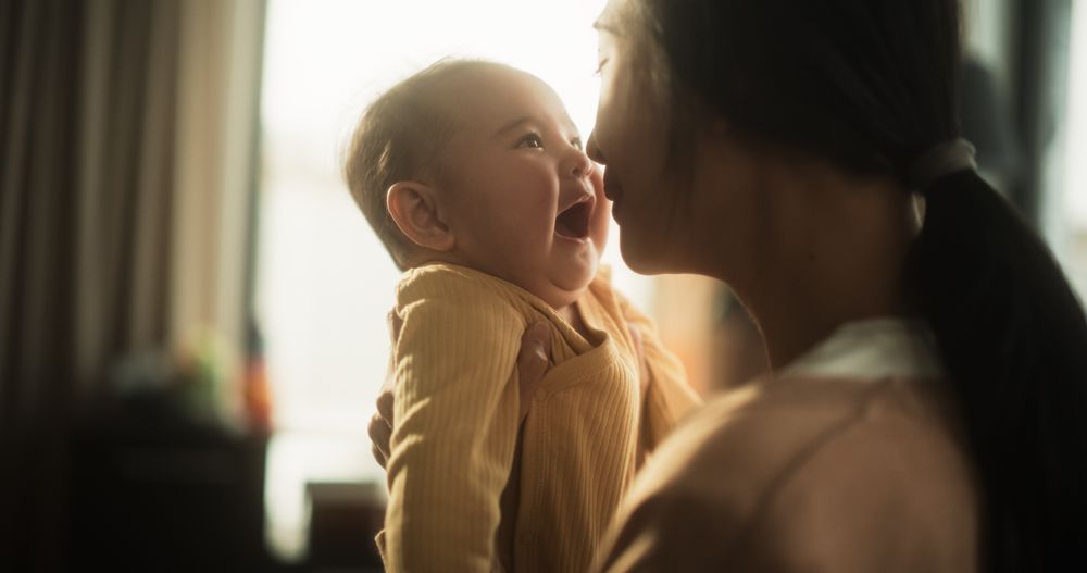 Motherly Affection Concept: Portrait of a Cute Happy Asian Baby Laughing