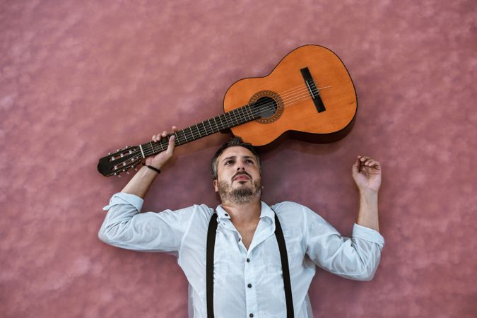 Man resting in water with guitar at seaside