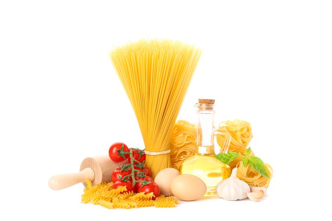 Pasta, olive oil, tomatoes, eggs, rolling pin and garlic isolated on light background. Uncooked whole wheat pasta