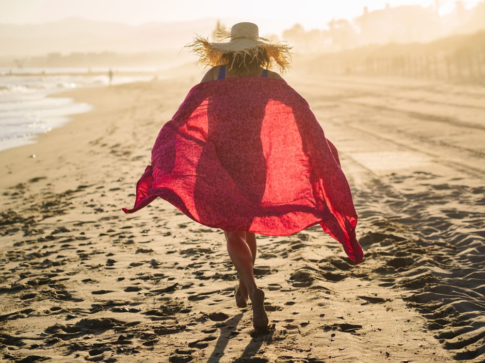 Woman with pink pareo on sandy beach