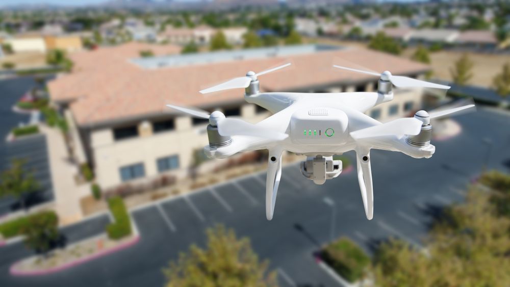Unmanned Aircraft System Quadcopter Drone In The Air Near Corporate Industrial Building