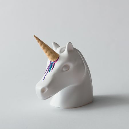 Painted unicorn head with colorful ice cream horn on bright  background