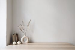 Elegant moody Scandinavian interior with vase and dry grass bouquet, old books and little mini pumpkins
