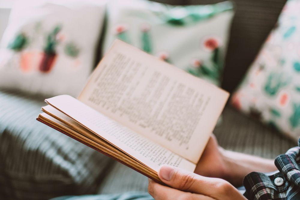 Cropped image of person reading a book in living room