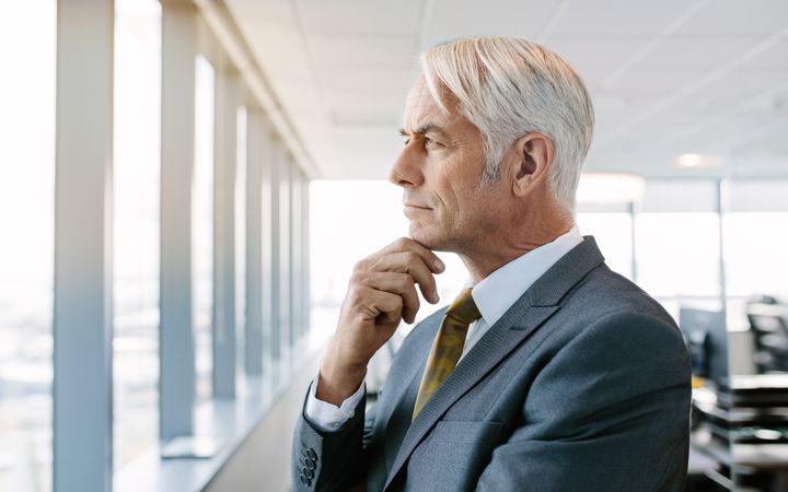 Thoughtful mature businessman standing by window