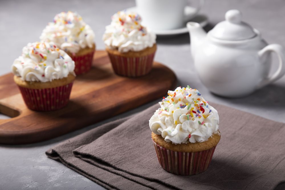 Tasty party cupcakes on the table. Cupcakes with whipped cream.