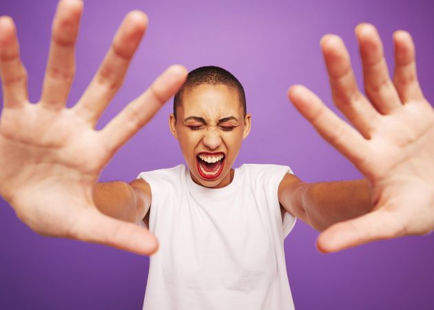 Wide angle portrait of a woman screaming with hands in front
