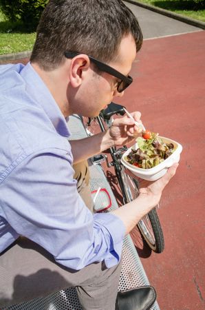 Young business man eating at lunch break outdoors