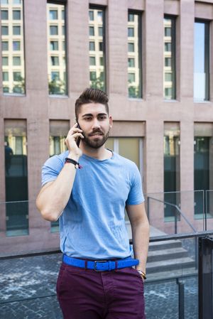 Portrait of man speaking by phone leaning outside