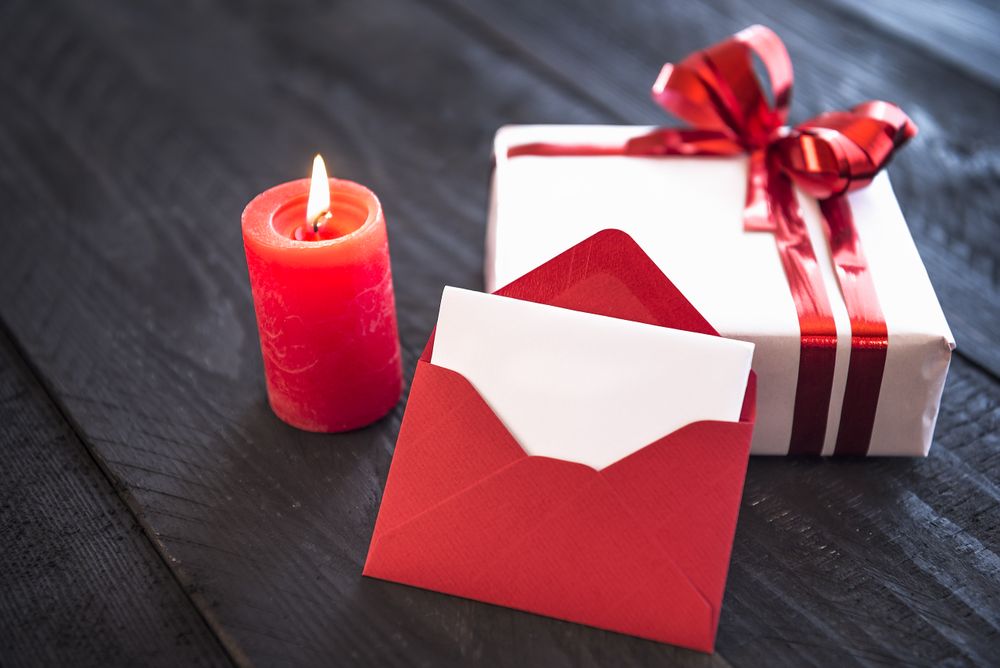 Candle, envelope and present on wooden table
