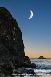 Crescent moon above quiet rocky beach at dusk, vertical composition 0gkPN0