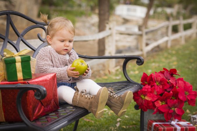 Young Toddler Child Sitting on Bench with Christmas Gifts Outside