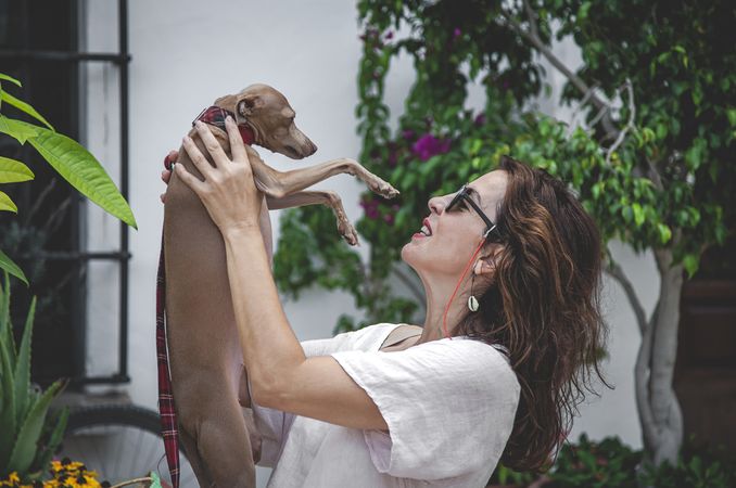 Woman kissing greyhound while relaxing on street