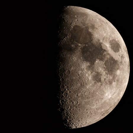 First quarter moon with detailed craters and rugged surface.