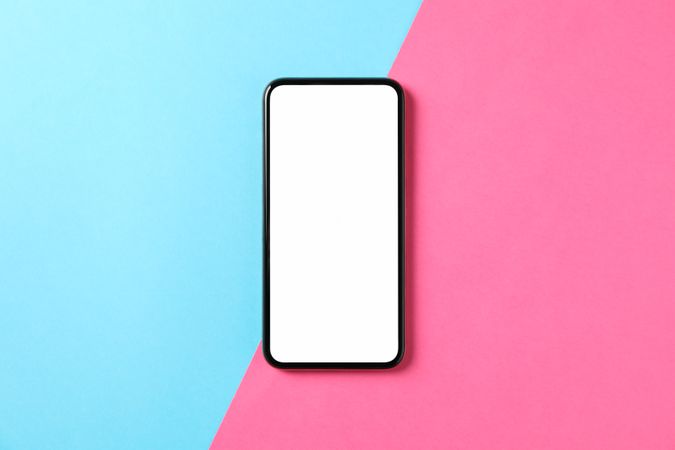 Phone with empty screen on two tone background, top view