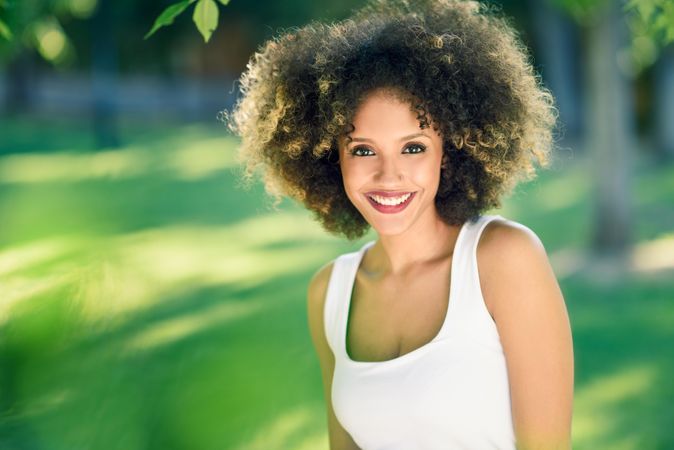 Portrait of smiling Black woman with afro hairstyle walking through park