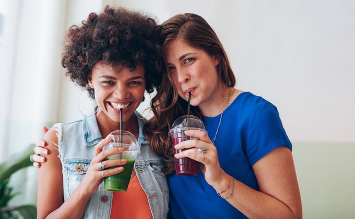 Portrait of happy young friends drinking fresh fruit juice together
