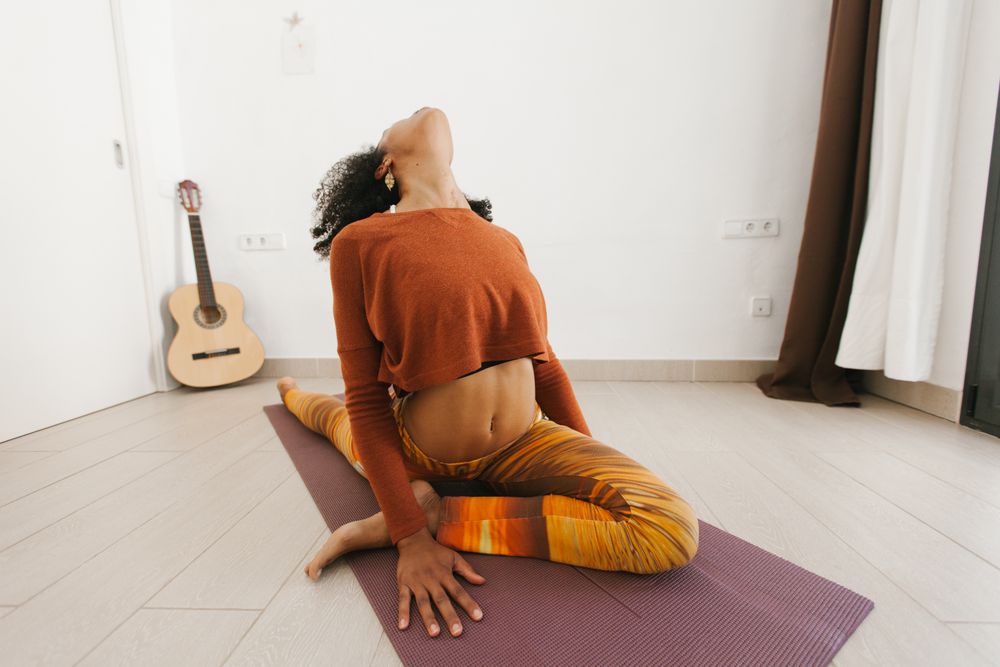 Sportive woman performing yoga pose in room