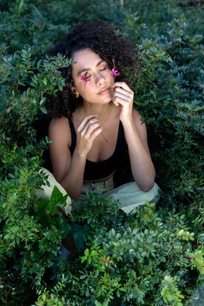 Beautiful young woman with afro hair surrounded by flowers