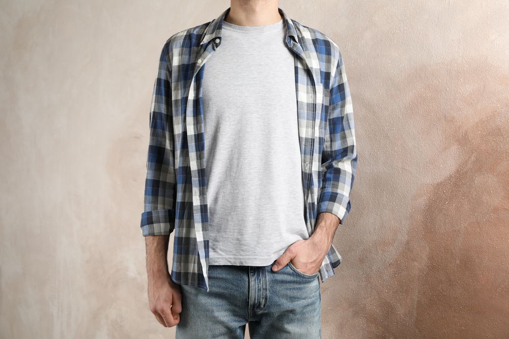 Men in grey t-shirt and checkered shirt against brown background, copy space
