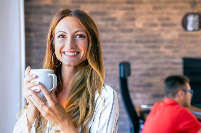 Happy businesswoman looking at camera with a cup of coffee