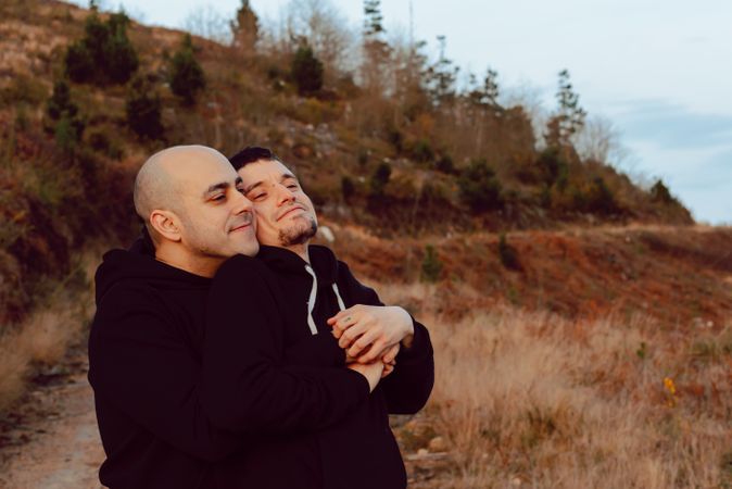 Men hugging on road on hill
