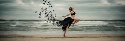 Young woman dancing with birds near sea