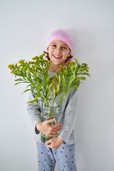 Happy boy in bandana with vase of goldenrods