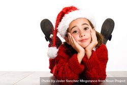 Child in santa outfit relaxing on stomach on ground resting her head on her hands 4dRXn0