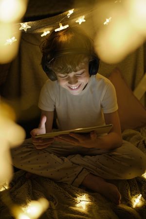 Smiling boy watching cartoon on tablet sitting in cozy tent