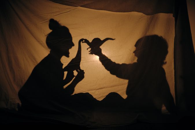Silhouette of mother and son playing in shadow theater
