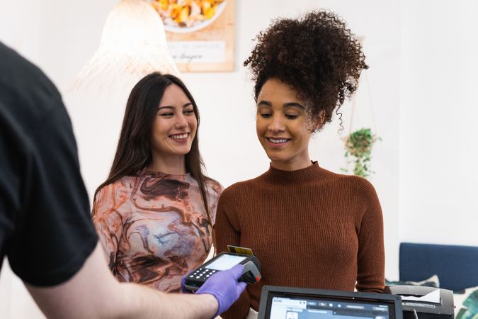 Diverse women making payment in restaurant