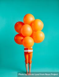 Girl holding orange balloons in front on blue background 4MKxx0