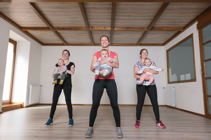 Mothers lifting babies in gym
