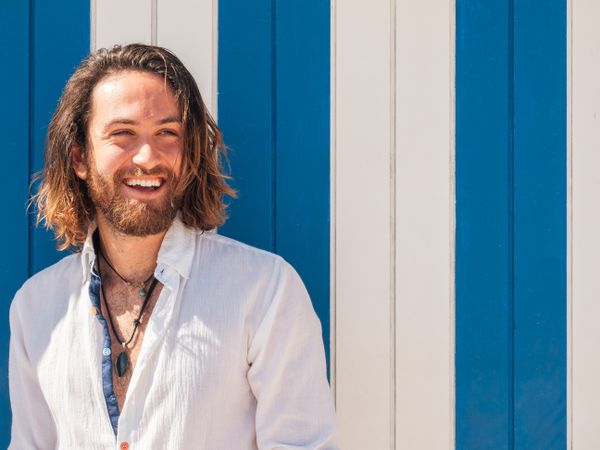 Cheerful guy standing near striped wall