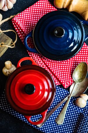 Top view of two red & blue cast iron pan on counter with kitchen towels ingredients