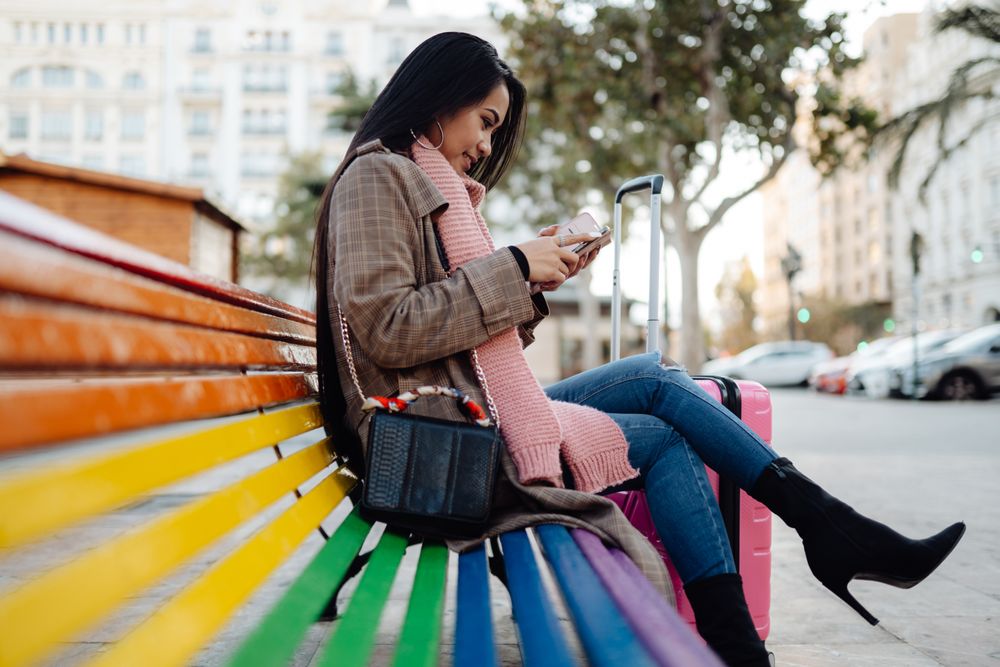 Asian traveler using smartphone on bench