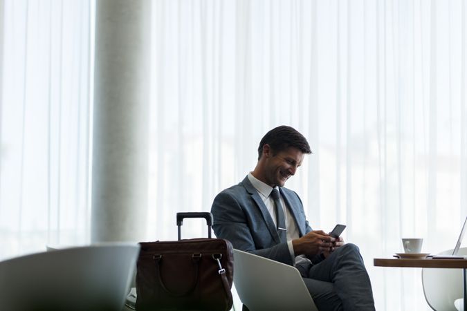 Businessman at airport lounge using mobile phone