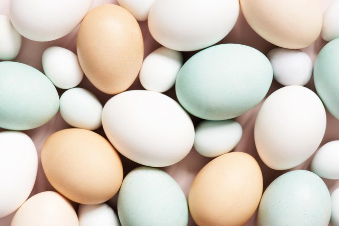 Close up of different colored eggs on pink background