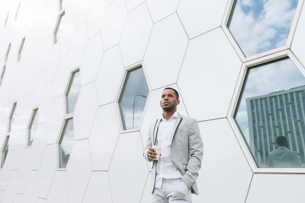 Black man with coffee standing in downtown