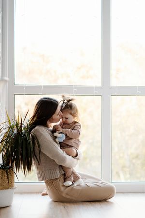 Mother her young daughter beside window