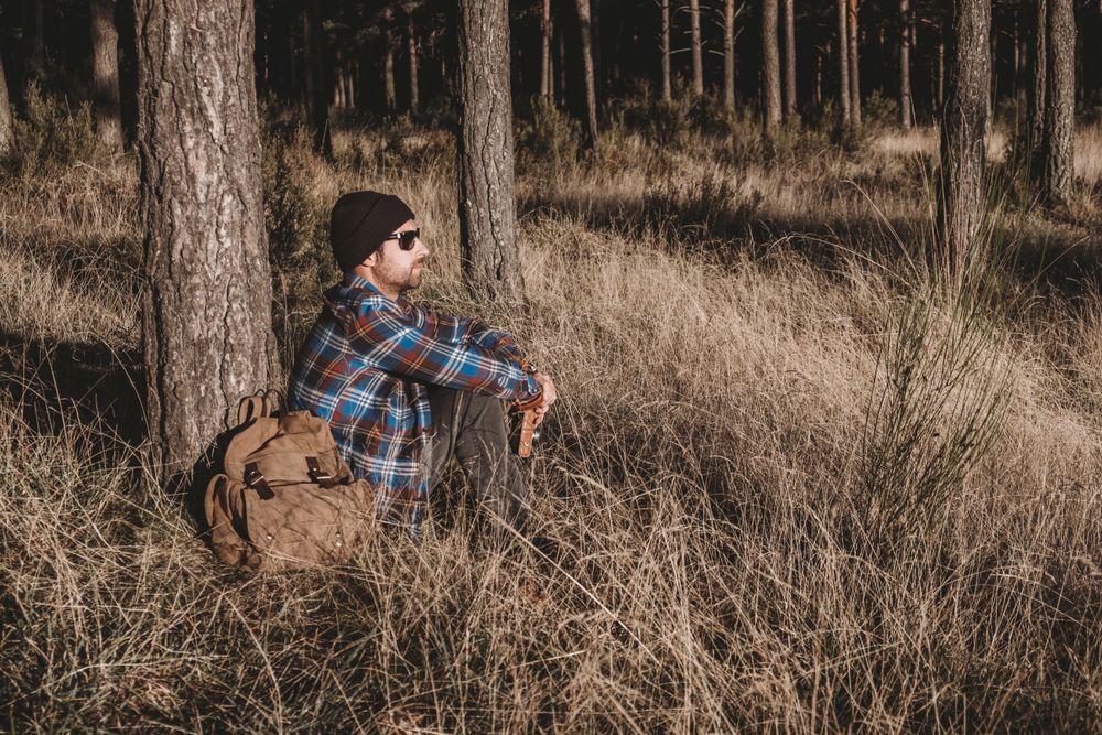 Relaxed tourist resting by tree in forest