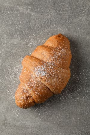 Croissant with powdered sugar on grey background, top view, vertical composition