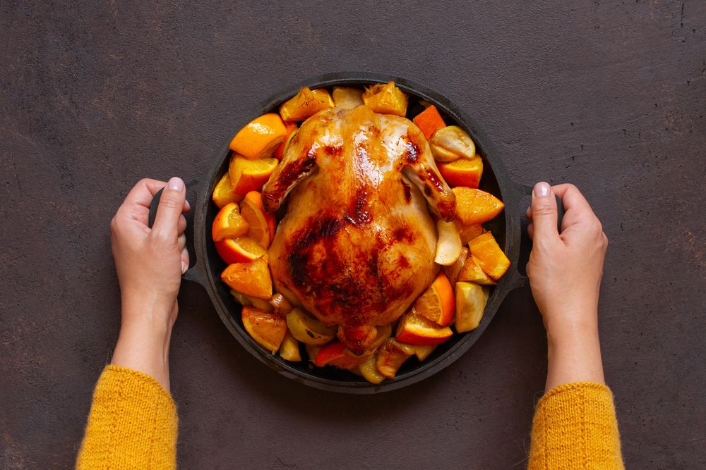 Person placing chicken in pot on table
