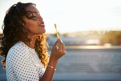 Side view of a Black woman blowing bubbles