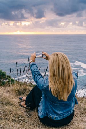 Female tourist taking shot of sea in twilight