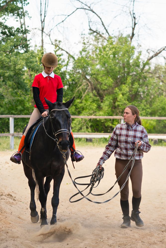 Young rider guided by instructor during equestrian training